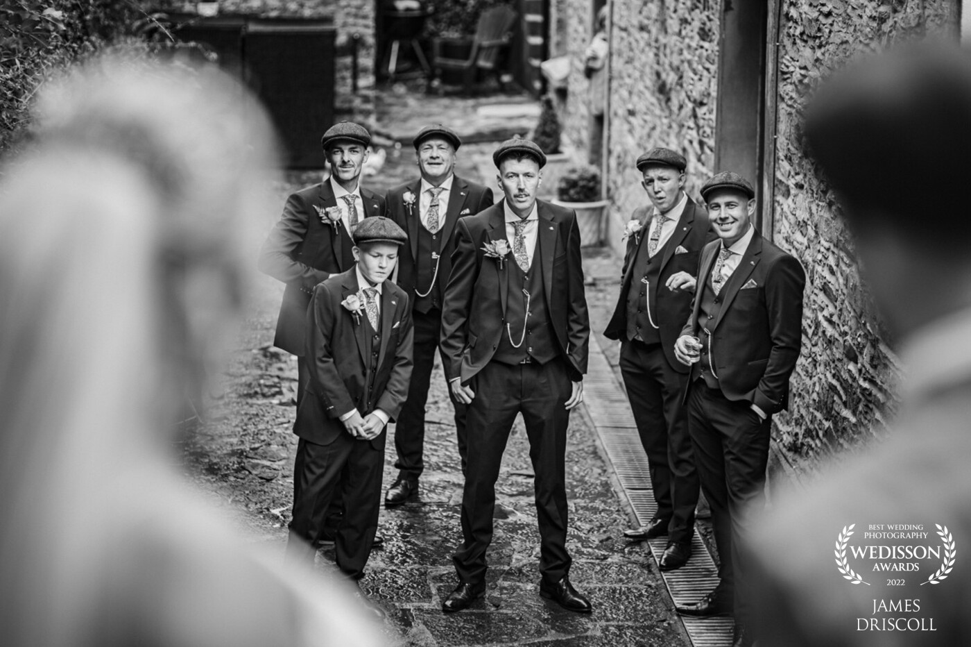 Peaky Blinder wedding. Bride and Groom went all out to dress up the entire Bridal party like the famous tv series Peaky Blinders. <br />
This image is shooting between the bride and groom down towards the Groomsmen.