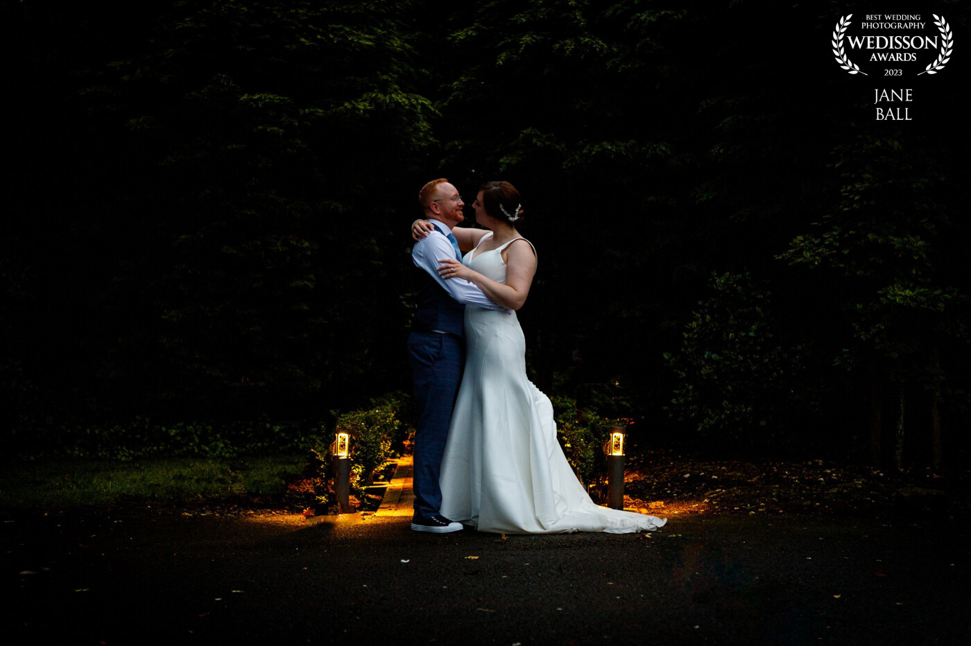 I'd taken my couple along this little path to the woodland beyond for their evening portraits. When we came back the lights had come on and this composition was there for the taking. Such a simple shot with the dark yew trees behind providing the clean background and the lights either side balancing the scene perfectly.