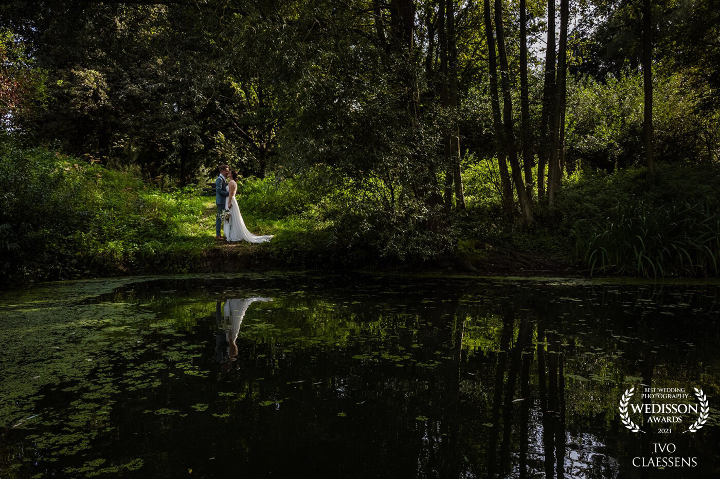 The photo was taken in Limburg, a beautiful and tranquil place in Heerlen, featuring a pond and lovely sunlight. I immediately noticed the reflection that could complete the entire scene. However, there was one problem: no way to get to the opposite side of the water where the bride and groom were. <br />
<br />
Now, you might wonder, "But you still took the photo." <br />
That's correct; we're not easily deterred. I took out the drone, positioned it in the middle of the pond, just above the water. This way, I found the perfect angle to capture this photo!