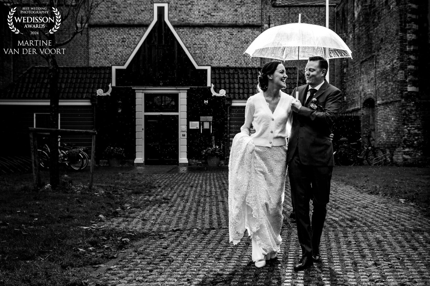 Your wedding day a rainy day? No worries time for some creativity! The wedding couple was cold (this was a winter wedding) but insisted on having outside photos in their favourite little Dutch town. They said, our love and laughter will keep us warm. WOW, what a couple, I love it!<br />
.<br />
Thank you Wedisson Team for awarding this photo with a Wedisson Award. Great to be part of the team.