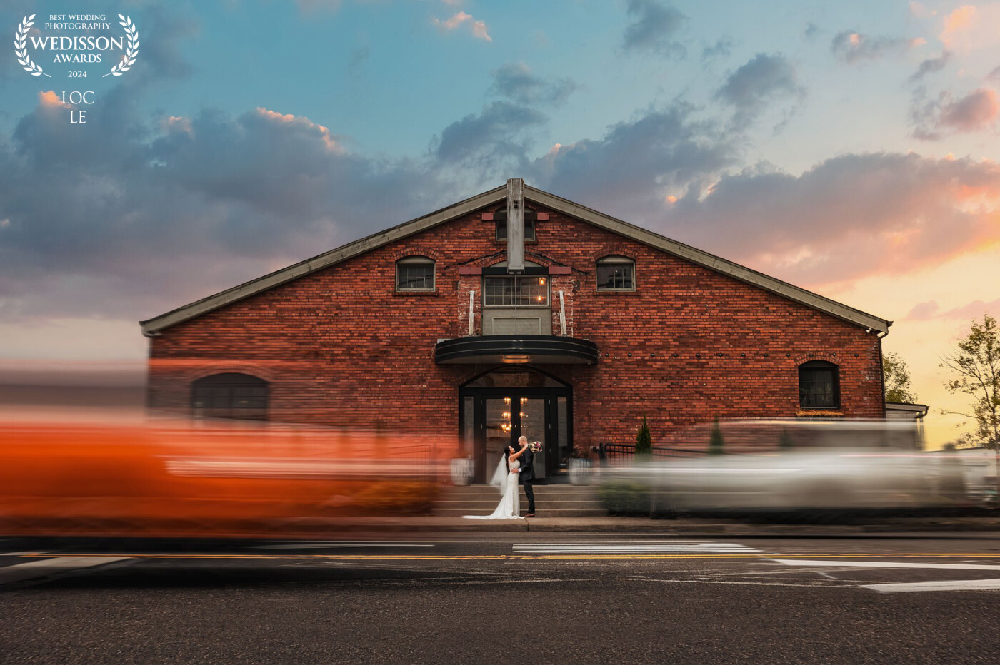 Embracing their special day amidst the vibrant downtown vibes. The magic of long exposure captures their love, creating a stunning frame with passing cars.