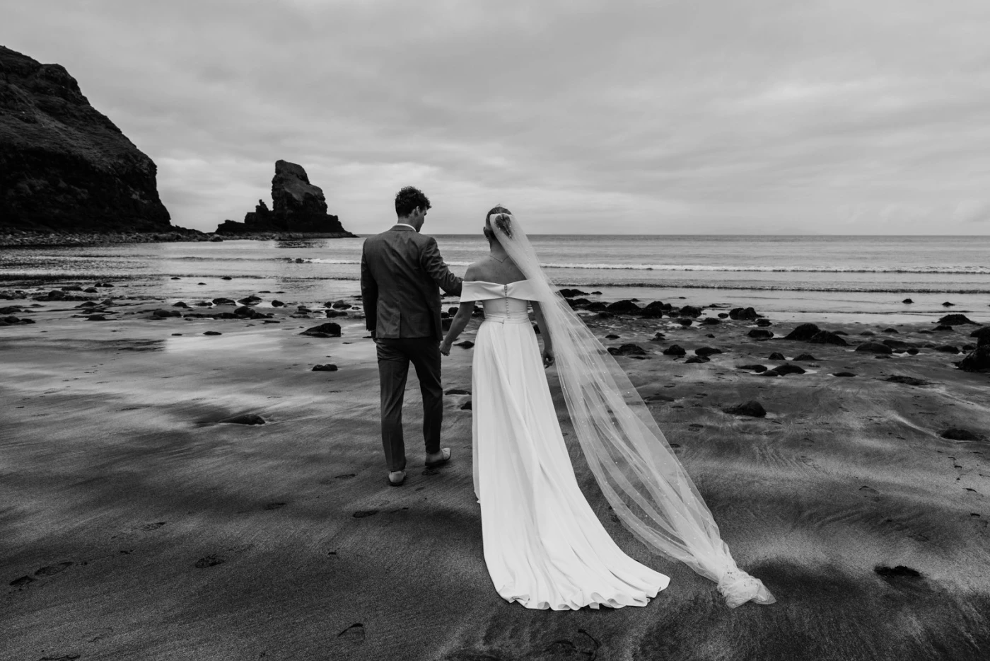 A beach with black and white sand contrasts perfectly with the bride and groom.