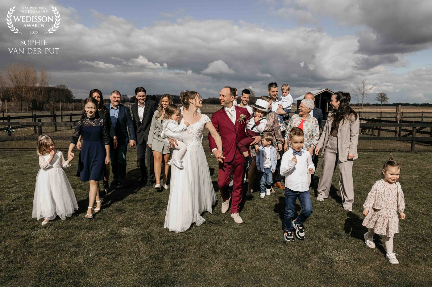 A wedding group photo filled with love and motion, captured in the fleeting moment when sunlight pierced through the clouds.