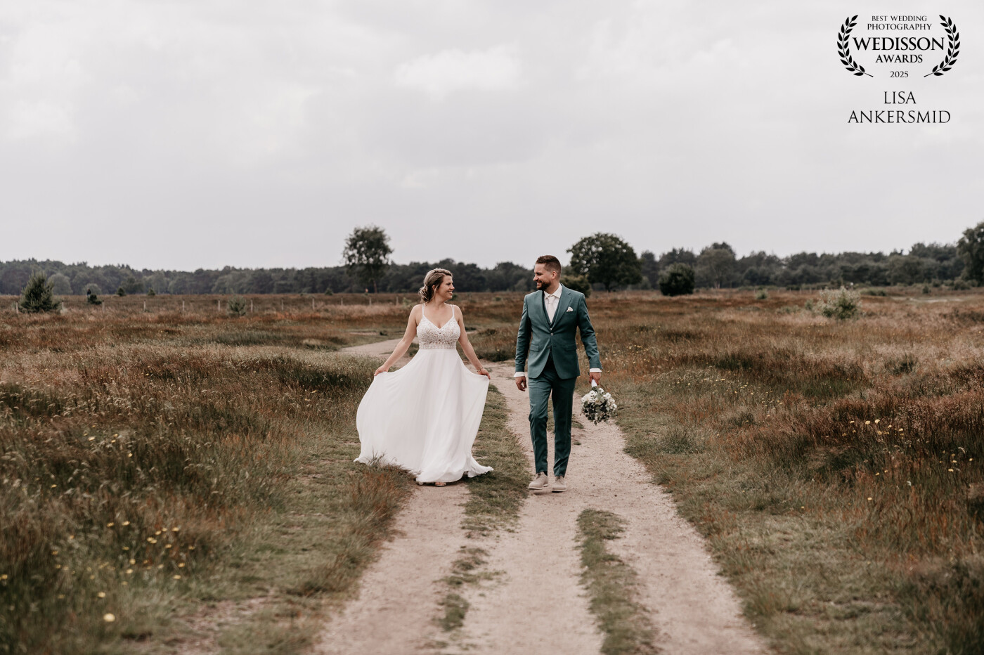 Voor het eerst naar het westen!<br />
Voor de bruiloft van Femke & Dennis reisde ik af naar het prachtige Bussummerheide (Goois Natuurreservaat) — een uitgestrekt en populair gebied vol paarse pracht. Met twee camera’s om mijn lijf en een drone in de lucht hebben we de mooiste beelden gemaakt van hun grote dag.<br />
<br />
Tijdens deze shoot trokken we er even met z’n drieën op uit, midden in de natuur — een soort mini loveshoot op je trouwdag. En nee, dat voelt écht niet ongemakkelijk. Juist even een rustmomentje samen, even ademhalen en genieten van elkaar.<br />
<br />
Tips voor een relaxte shoot op je bruiloft:<br />
– Plan een rustig moment, weg van de drukte<br />
– Trek schoenen aan die lekker lopen (je kunt altijd even wisselen)<br />
– Laat los dat je ‘mooi op de foto’ moet — ik zorg daarvoor 😉<br />
– Geniet vooral van elkaar, dan volgt de magie vanzelf<br />
<br />
Lieve Femke & Dennis, dankjewel voor jullie vertrouwen. Wat een eer om dit voor jullie vast te mogen leggen.