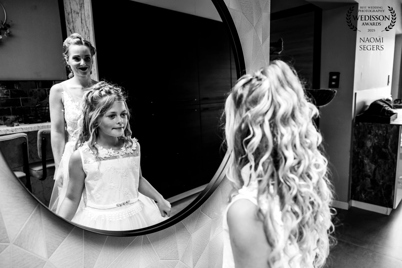 A special moment between a mother and her daughter on the morning of the wedding. Both standing before the mirror to look at their reflection. Their expressions reflect the deep emotional connection between them. This photo is a powerful sense of love, pride, and the beginning of a new chapter.