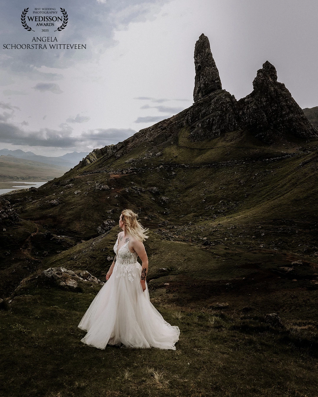 A bride stands gracefully on a rugged Scottish mountain, her dress flowing in the wind like a whisper of romance. Surrounded by wild beauty and misty peaks, her love story feels as timeless as the land beneath her feet.