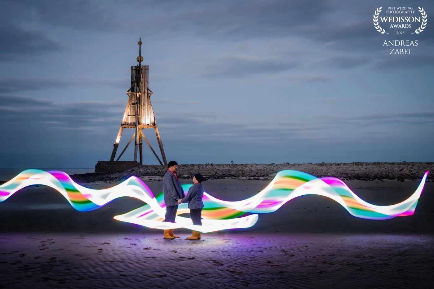 Im Juni durfte ich ein ganz besonders herzliches Brautpaar nach Cuxhaven begleiten. Die Trauung fand morgens im historischen Leuchtturmdenkmal Obereversand statt – eine Kulisse, wie man sie sich als Hochzeitsfotograf nur wünschen kann.<br />
Zwischen uns stimmte einfach die Chemie, sodass wir den ganzen Tag gemeinsam verbrachten. Abends gab es eine köstliche Edelfischplatte – und als wäre das noch nicht perfekt genug, machten wir uns im Sonnenuntergang auf ins Weltnaturerbe Wattenmeer, zur legendären Kugelbake.<br />
Die Kamera stand auf dem Stativ, Selbstauslöser auf 10 Sekunden – ich hatte nur diesen kurzen Moment, um die Spur perfekt zu zeichnen. Es brauchte mehrere Anläufe, matschige Schuhe und jede Menge Geduld. 😅<br />
Danke von Herzen an Verena und Andre – ihr wart nicht nur geduldige Models, sondern auch fantastische Begleiter. Ich weiß, dass man in der Hochzeitsnacht eigentlich anderes im Sinn hat, als mit dem Fotografen durchs Watt zu laufen. 💛