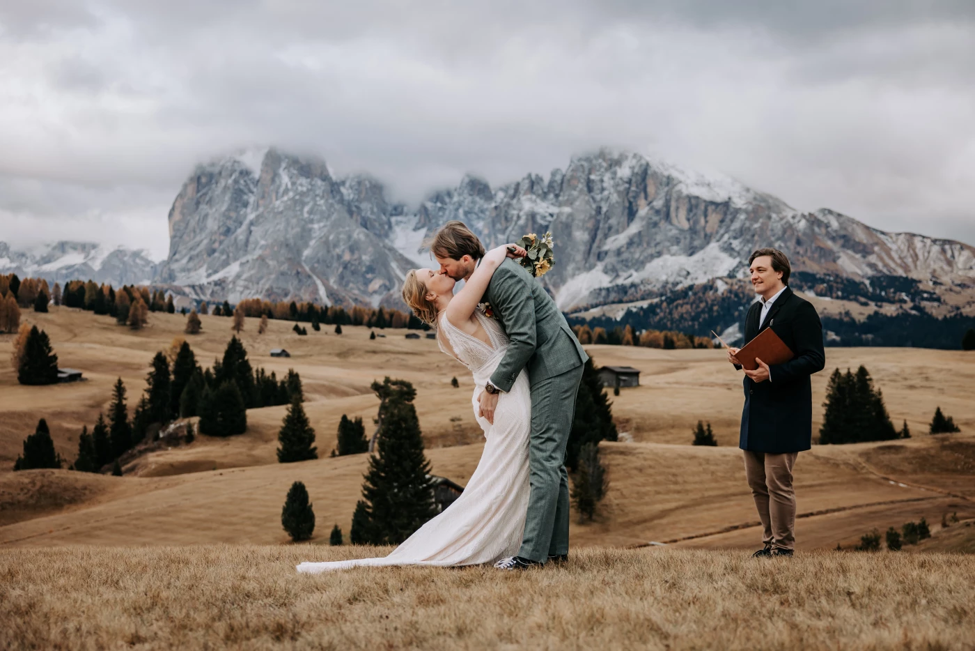 As the ceremony ends, they lean into their first kiss as newlyweds, laughter still in the air. Behin...